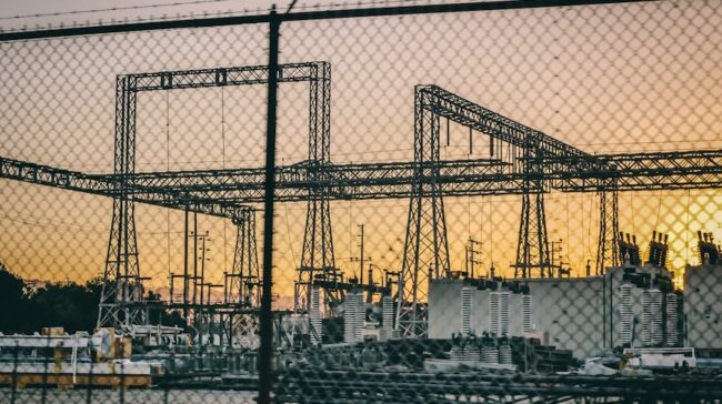 Industrial electric power substation photographed at sunset with fence in the foreground. - Photo by Kindel Media on Pexels
