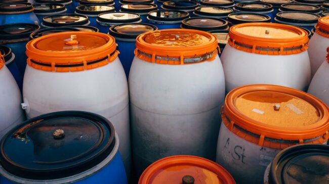 Close-up of blue and white plastic barrels with orange lids in storage area. - Photo by Markus Winkler on Pexels