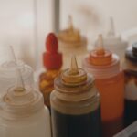 Close-up of various condiment squeeze bottles in a food preparation setting. - Photo by Tima Miroshnichenko on Pexels