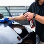A man cleaning a black car hood with a spray and microfiber cloth. - Photo by Torque Detail on Pexels
