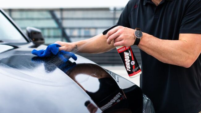 A man cleaning a black car hood with a spray and microfiber cloth. - Photo by Torque Detail on Pexels