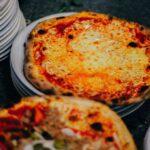 Close-up of a delicious cheese pizza on stacked white plates, perfect for a comforting meal. - Photo by Mathias Reding on Pexels