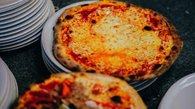Close-up of a delicious cheese pizza on stacked white plates, perfect for a comforting meal. - Photo by Mathias Reding on Pexels